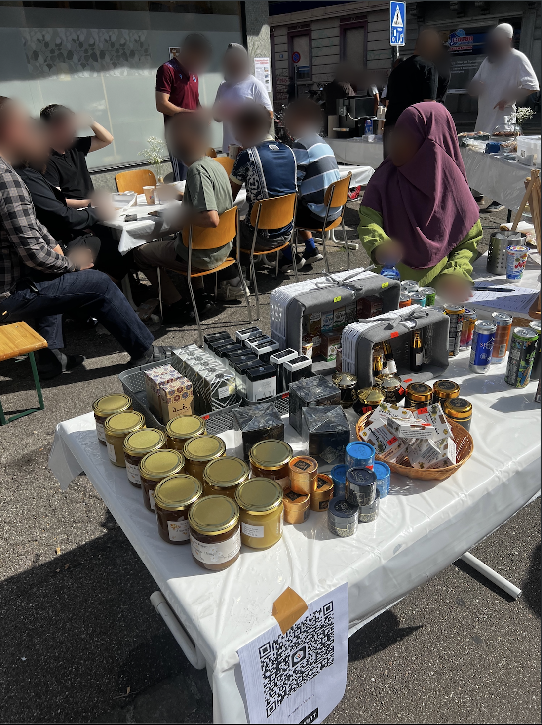 Verkaufstisch mit Honig, Parfums und Getränken, im Hintergrund Sitzplätze für Besucher:innen